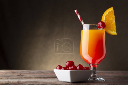 Téléchargez les photos : Cocktail froid au lever du soleil à la tequila, jus de grenade et jus d'orange décoré de tranches d'orange et de cerises de marasquin - en image libre de droit
