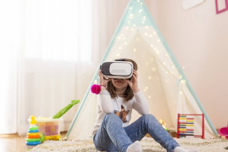 Photo for Little girl wearing virtual reality headset, playing in a playoom and having fun - Royalty Free Image