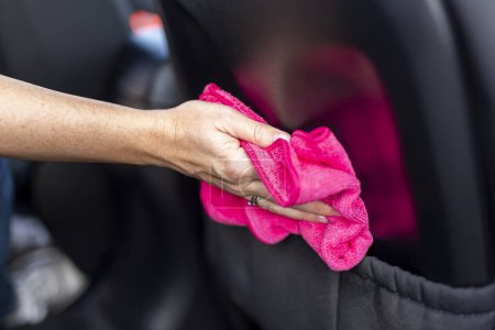 Téléchargez les photos : Détail de la main féminine essuyant la poussière et polissant les pièces intérieures de la voiture avec une lingette de nettoyage - en image libre de droit