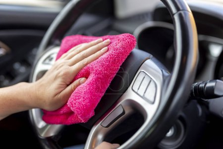 Foto de Detalle de la mano femenina limpiando el polvo y pulido de piezas de interior del coche con paño de limpieza - Imagen libre de derechos