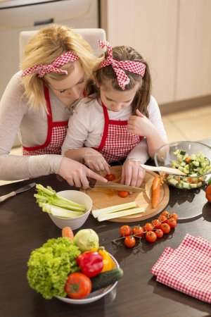 Foto de Madre e hija cortando verduras y haciendo ensalada - Imagen libre de derechos