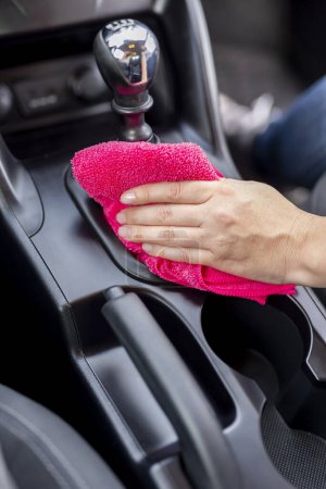 Foto de Detalle de la mano femenina limpiando el polvo y pulido de piezas de interior del coche con paño de limpieza - Imagen libre de derechos