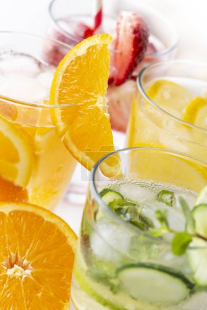 Téléchargez les photos : Détails des verres d'eau infusée aux fraises fraîches, feuilles de tilleul et de menthe, citron et orange - en image libre de droit
