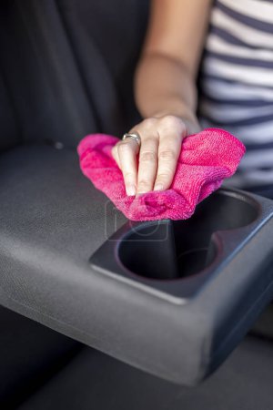 Téléchargez les photos : Détail de la main féminine essuyant la poussière et polissant les pièces intérieures de la voiture avec une lingette de nettoyage - en image libre de droit