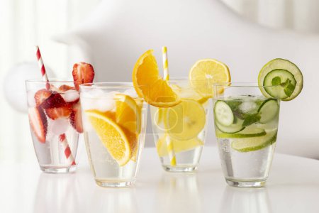 Téléchargez les photos : Verres d'eau infusée aux fraises fraîches, citron vert, concombre et feuilles de menthe, citron et orange. Focus sur la tranche d'orange sur le verre - en image libre de droit