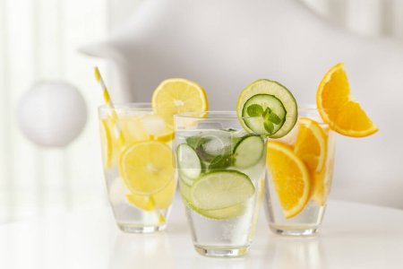 Foto de Vasos de agua infundida con lima fresca, pepino y hojas de menta, limón y naranja - Imagen libre de derechos