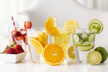 Foto de Vasos de agua infundida con fresas frescas, lima, pepino y hojas de menta, limón y naranja. Concéntrate en la rebanada de naranja en el vaso - Imagen libre de derechos