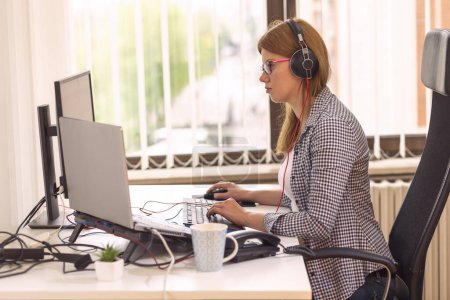 Foto de Operador de centro de llamadas sentado en un escritorio en una oficina, con un auricular y recibir llamadas - Imagen libre de derechos
