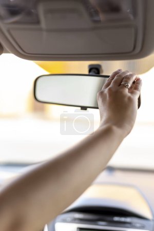 Photo for Detail of female hand adjusting rearview mirror in the car before driving - Royalty Free Image