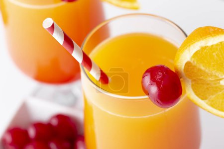 Photo for High angle view of two cold tequila sunrise cocktails with tequila, pomegranate juice and orange juice decorated with slices of orange and maraschino cherries. Focus on the cherry on the glass - Royalty Free Image