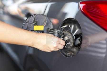 Photo for Detail of female hand opening car fuel tank door in order to refuel car at a petrol station; car tank refilling at a gas station - Royalty Free Image