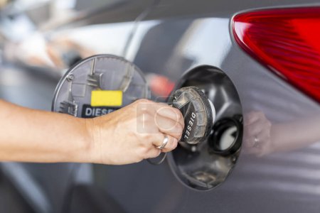 Photo for Detail of female hand opening car fuel tank door in order to refuel car at a petrol station; car tank refilling at a gas station - Royalty Free Image
