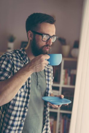 Photo for Handsome man standing next to a window, drinking coffee - Royalty Free Image