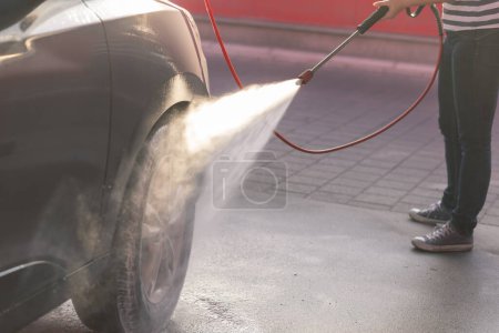 Photo for Detail of female hands washing a car tires with hot hight pressure water and detergent - Royalty Free Image