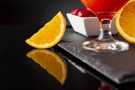 Foto de Detalle de cócteles fríos de tequila al amanecer con tequila, zumo de granada y zumo de naranja decorado con rodajas de cerezas de naranja y maraschino. Concéntrate en la rebanada de naranja - Imagen libre de derechos