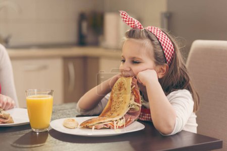 Téléchargez les photos : Mère et fille prennent le petit déjeuner dans la cuisine ; fille refuse de manger - en image libre de droit