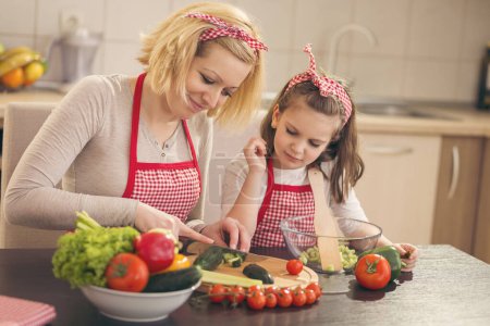 Photo for Mother and daughter cutting vegetables and making salad - Royalty Free Image
