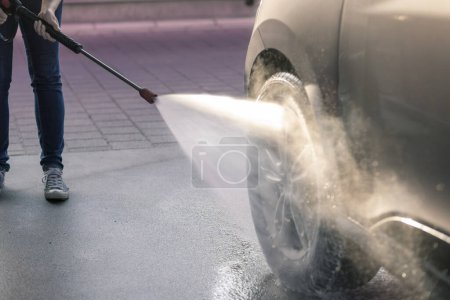 Photo for Detail of female hands washing a car tires with hot hight pressure water and detergent - Royalty Free Image