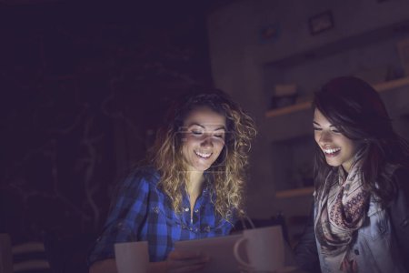 Foto de Dos amigos sentados en un café, navegando por la red en una tableta y publicando en las redes sociales - Imagen libre de derechos