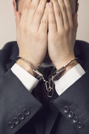Photo for Businessman in a suit with handcuffs, arrested, holding his head in his hands. Selective focus - Royalty Free Image
