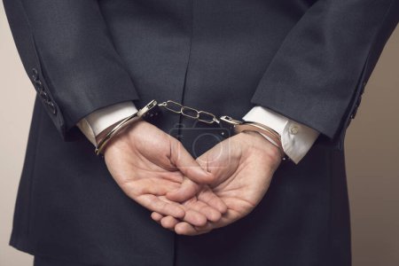 Photo for Business man in a suit with handcuffs, under arrest for corruption and bribery. Selective focus - Royalty Free Image