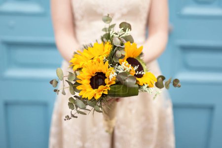 Photo for Close up of a bride in a wedding dress holding a sunflower wedding bouquet. Selective focus - Royalty Free Image