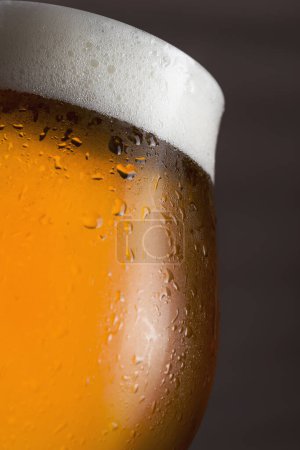 Photo for Close up of a wet glass of cold light beer with foam. Selective focus - Royalty Free Image