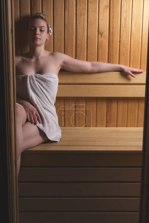 Foto de Hermosa joven mujer relajándose y disfrutando de una sesión de sauna finlandesa - Imagen libre de derechos