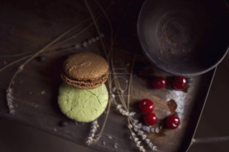 Téléchargez les photos : Vue de dessus des biscuits au macaron sur un plateau en bois, avec un bol, des cerisiers et des fleurs de lavande placés à côté. Concentration sélective - en image libre de droit