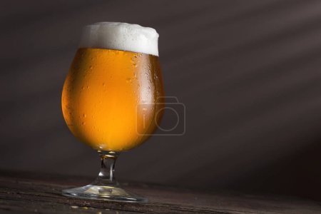 Foto de Vaso de cerveza fría pálida sobre una mesa rústica de madera - Imagen libre de derechos