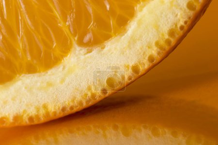 Foto de Detalle de una rebanada de fruta naranja aislada sobre fondo naranja. Enfoque selectivo - Imagen libre de derechos