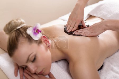 Photo for Woman lying in a beauty parlour, enjoying relaxing back massage with chocolate - Royalty Free Image