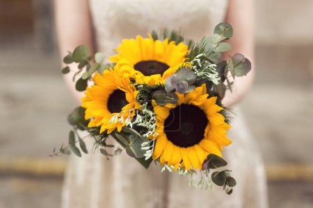 Photo for Close up of a bride in a wedding dress holding a sunflower wedding bouquet. Selective focus - Royalty Free Image