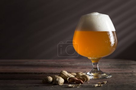 Foto de Vaso de cerveza ligera fría sin filtrar en una mesa de pub de madera rústica - Imagen libre de derechos