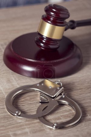 Photo for Close up of a judge gavel and handcuffs in a courtroom. Focus on the handcuffs - Royalty Free Image