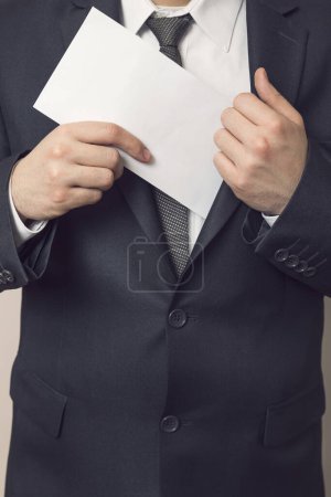 Photo for Detail of a man in a suit placing envelop with money in his jacket pocket. Selective focus - Royalty Free Image