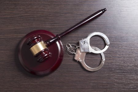 Photo for Top view of a judge gavel placed on a desk with handcuffs set next to it - Royalty Free Image