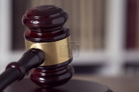 Photo for Close up of a judge gavel and law books in the background of a courtroom. Selective focus - Royalty Free Image