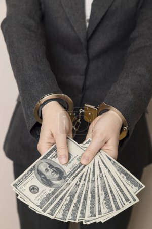Photo for Business woman in a suit with handcuffs, arrested, offering bribery money for her releasing. Selective focus - Royalty Free Image