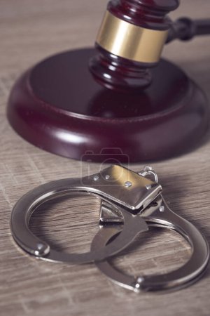 Photo for Close up of a judge gavel and handcuffs in a courtroom. Selective focus - Royalty Free Image