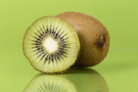 Photo for Close up of a cross section and a whole kiwi fruit isolated on a green background. Focus stacked image - Royalty Free Image