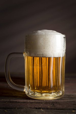 Photo for Glass of cold pale beer placed on a rustic wooden table - Royalty Free Image