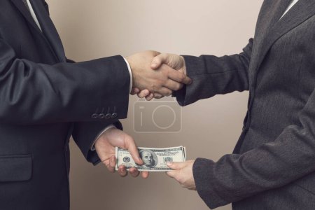 Foto de Un empresario corrupto sellando el trato con un apretón de manos y recibiendo un soborno - Imagen libre de derechos