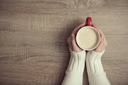 Téléchargez les photos : Vue du dessus d'une main féminine tenant une tasse de café sur la table en bois - en image libre de droit