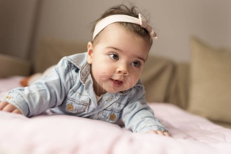 Photo for Beautiful baby girl crawling and rolling over in bed - Royalty Free Image