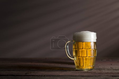 Foto de Jarra de cerveza fría y pálida colocada sobre una mesa rústica de madera - Imagen libre de derechos