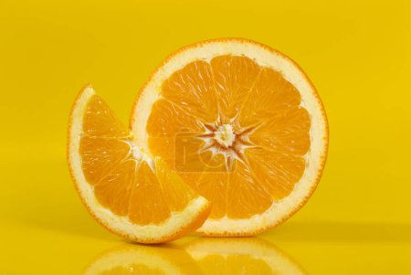 Téléchargez les photos : Plan studio d'une coupe transversale et d'une tranche d'un fruit orange isolé sur fond jaune. Tous au point en utilisant la technique d'empilage de mise au point. Focus image empilée - en image libre de droit