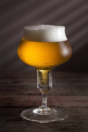 Foto de Vaso de cerveza fría sobre una mesa rústica de madera - Imagen libre de derechos