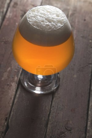 Foto de Vaso de cerveza fría sin filtrar sobre una mesa de madera rústica. Concéntrate en la espuma - Imagen libre de derechos