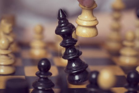 Foto de Primer plano de un tablero de ajedrez de madera y piezas, reina blanca tomando un rey negro. Enfoque selectivo - Imagen libre de derechos